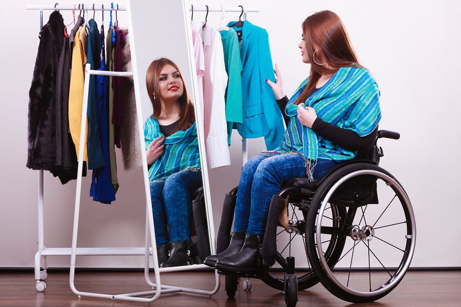 A woman in a wheelchair picks out an outfit.